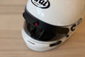 White helmet with Arai logo on a wooden surface