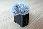 black audio recorder or microphone, resting on a light-colored wooden surface.